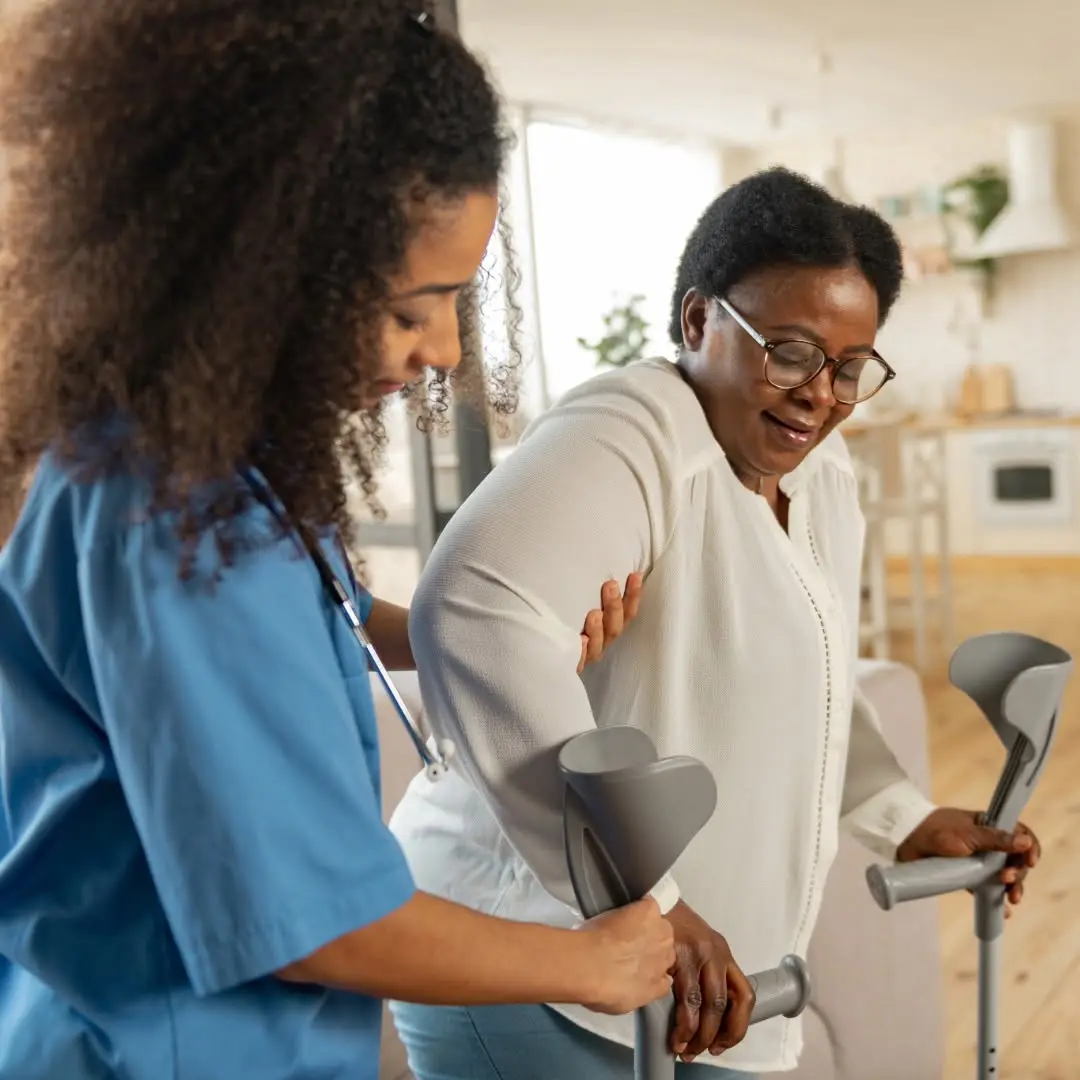 COHME caregiver helping a client walk with crutches at home