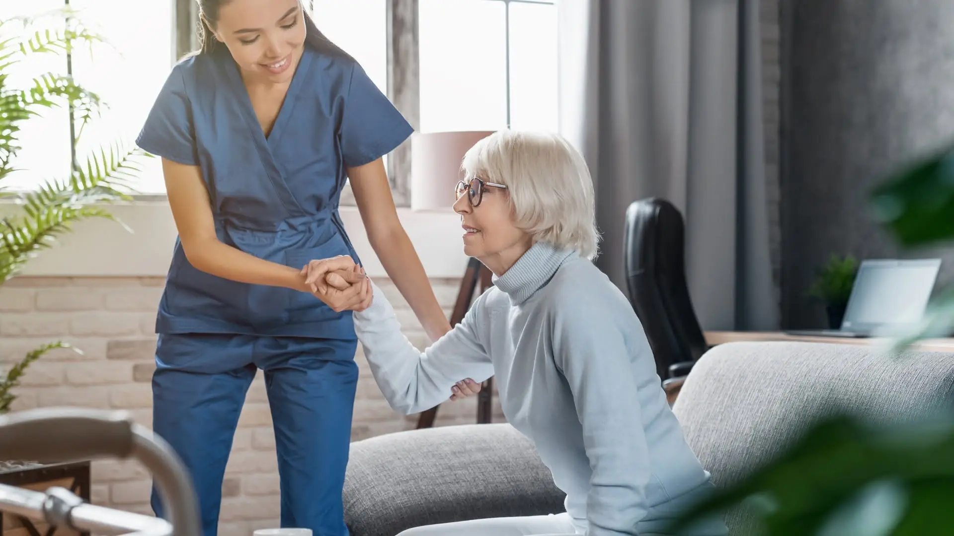 COHME aide helping an elderly woman stand safely in her living room