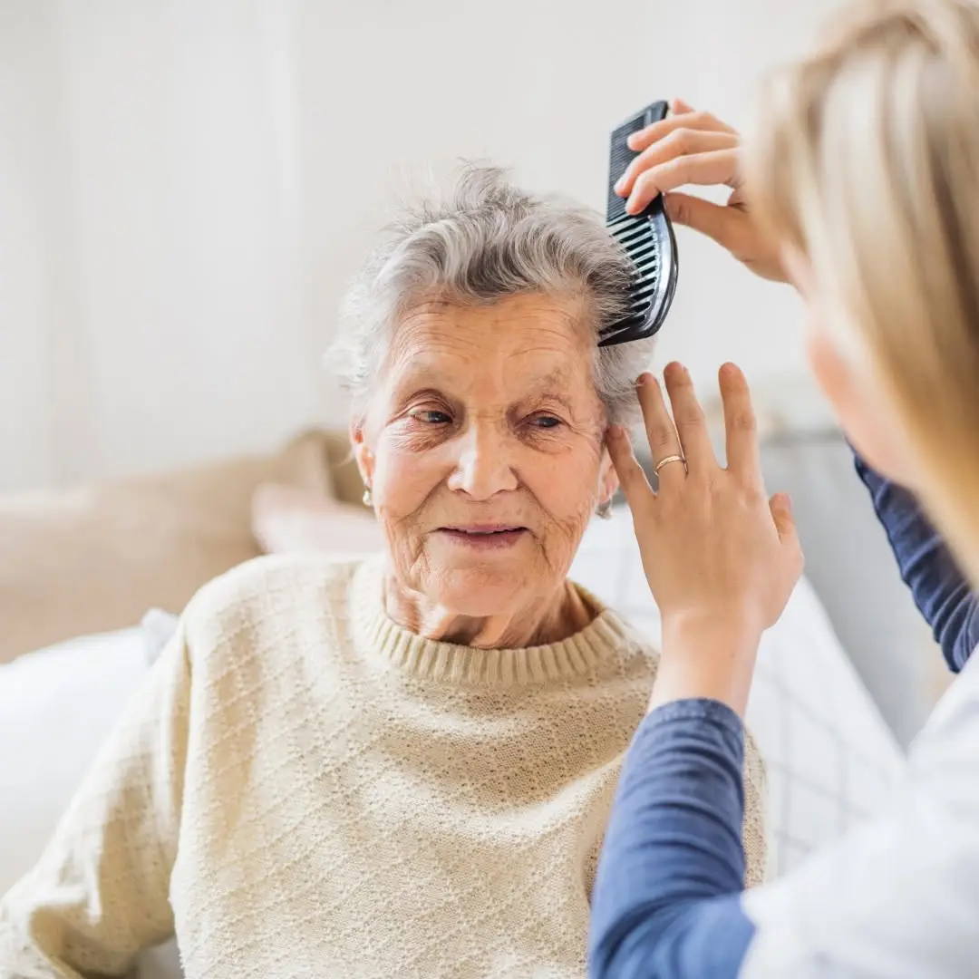 Caregiver gently brushing an elderly woman's hair