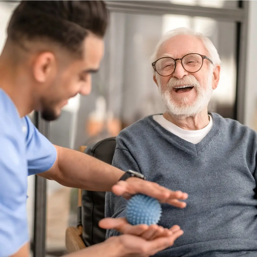 Caregiver sharing a laugh with an elderly man during an activity